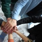 A top view of business people joining hands in a circle, symbolizing unity, collaboration, and shared success in the workplace.